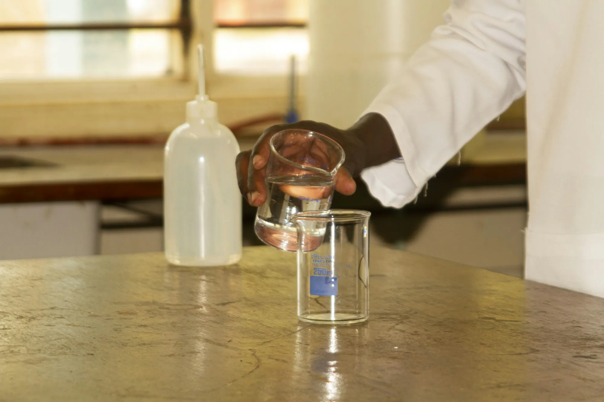 Water Testing & Analysis in Aliso Viejo, CA Lab worker pouring a water sample into a glass beaker